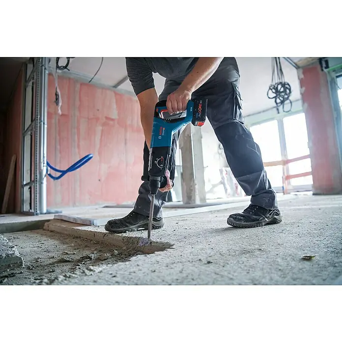 Bosch Professional AMPShare 18V Akku-Bohrhammer GBH 18V-28 D - 18 V, Ohne Akku - Ein Bauarbeiter benutzt einen Bosch Akku-Bohrhammer zum Aufbrechen von Beton. Das Werkzeug ist blau und hat einen schwarzen Griff.