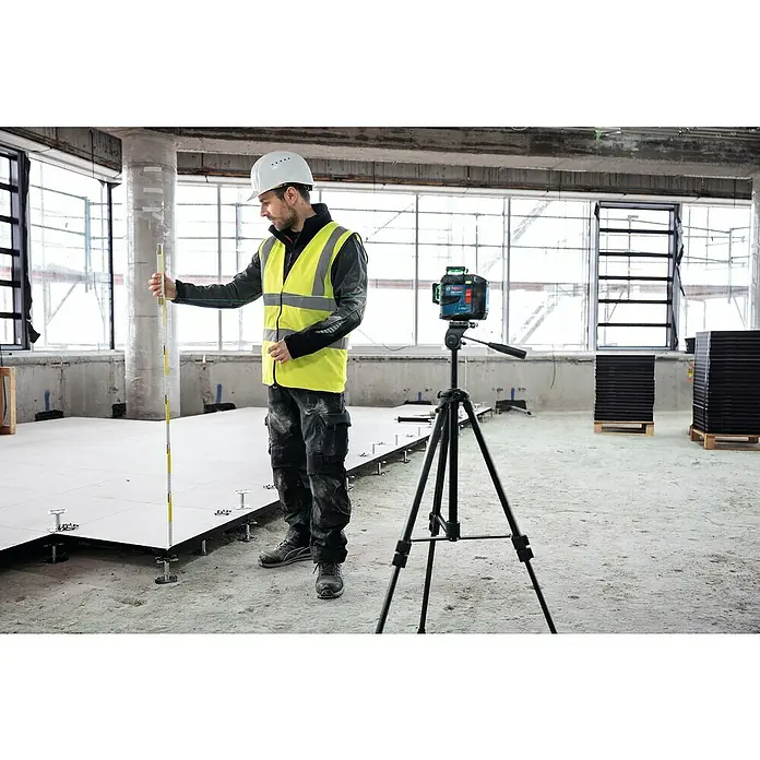 Bosch Professional Linienlaser GLL 80-33 G - 5 -tlg., Max. Arbeitsbereich: 0 m - 30 m - Bauarbeiter überprüft mit einem Laser-Nivelliergerät und einem Messstab die Ebenheit eines erhöhten Bodenbelags auf einer Baustelle.