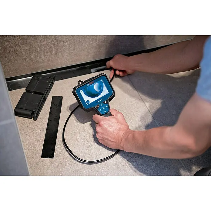 Bosch Professional Inspektionskamera GIC 12V-5-27 C - 12 V, Ohne Akku, Batteriebetrieben - Ein Mann verwendet eine Bosch Inspektionskamera, um eine schwer zugängliche Stelle unter einer Wand zu inspizieren. Das Gerät zeigt ein klares Bild.