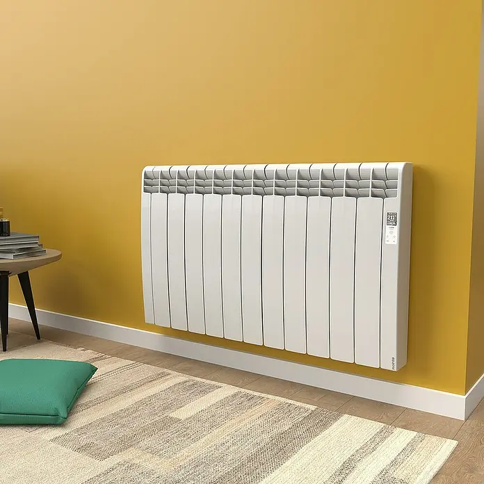 Rointe Emisor térmico Delta - 1.210 W, Blanco, 9,7 x 99,3 x 58,5 cm, Fluido - Detalle de un radiador blanco moderno en una pared amarilla, que combina confort y estilo.
