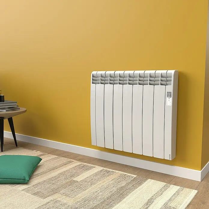 Rointe Emisor térmico Delta - 770 W, Blanco, 9,7 x 67,5 x 58,5 cm, Fluido - Un radiador blanco moderno montado en una pared amarilla con controles digitales. Proporciona calidez y confort a la habitación con un diseño elegante.