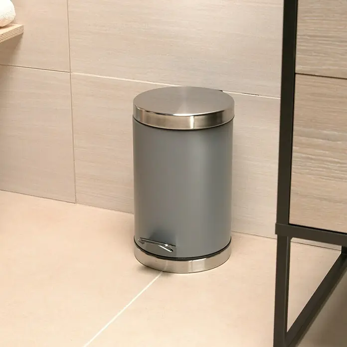 Venus Treteimer Kenzie - 3 l, Edelstahl, Grau - Ein grauer Treteimer mit einem silbernen Deckel und Fußpedal steht in einem Badezimmer. Praktisch und stilvoll für jeden Raum!