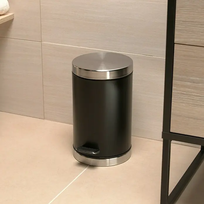 Venus Treteimer Kenzie - 3 l, Edelstahl, Schwarz - Ein schwarzer, zylinderförmiger Treteimer mit silbernem Deckel und Fußpedal steht in einem Badezimmer.