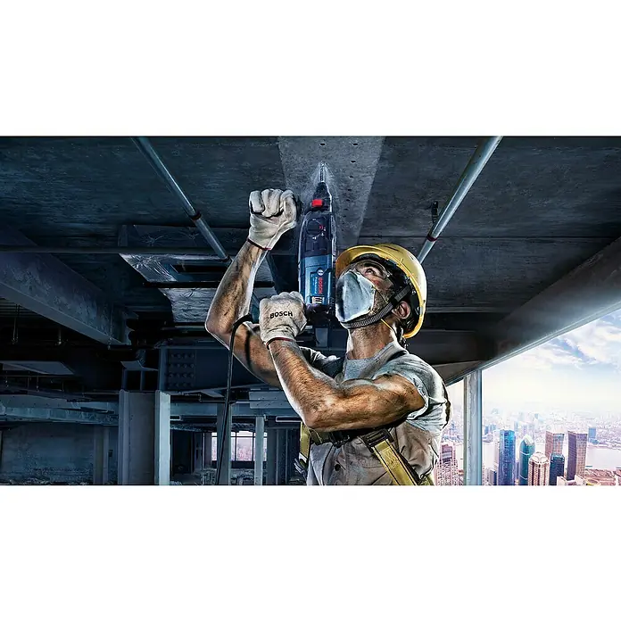 Bosch Professional Kombihammer GBH 240 - 790 W, 2,7 J, SDS-Plus-Aufnahme - Ein Bauarbeiter mit Schutzhelm bohrt mit einem Bosch Bohrhammer Löcher in eine Betondecke, umgeben von Stahlträgern.