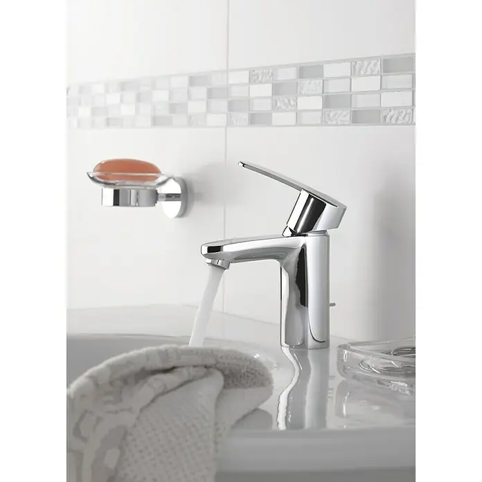 Grohe Essentials Seifenschale - Mit Halterung, Chrom, Glänzend - Nahaufnahme einer glänzenden Armatur mit Wasserhahn im Badezimmer, neben einer Seifenschale und einem hellen Handtuch.