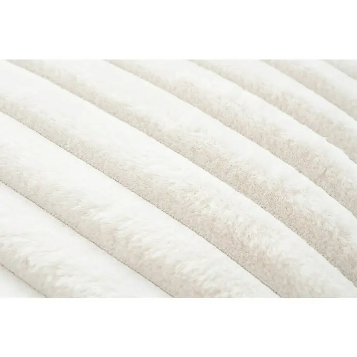 Kissen Plush - Ivory, 45 x 45 cm, 100 % Polyester - Nahaufnahme einer flauschigen, weißen Tagesdecke mit parallelen, erhöhten Streifen, die eine weiche, strukturierte Oberfläche zeigt.