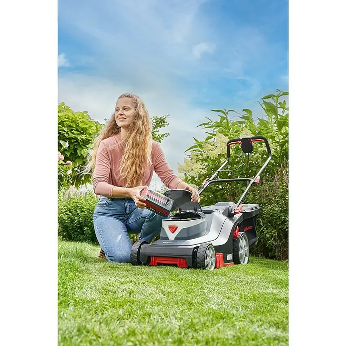 AL-KO Comfort Akku-Rasenmäher 38.5 Li - 36 V, 1 Akku, 4 Ah, Schnittbreite: 38 cm - Eine Frau setzt einen Akku in einen AL-KO Rasenmäher auf einer grünen Wiese ein, um ihren Garten zu pflegen.