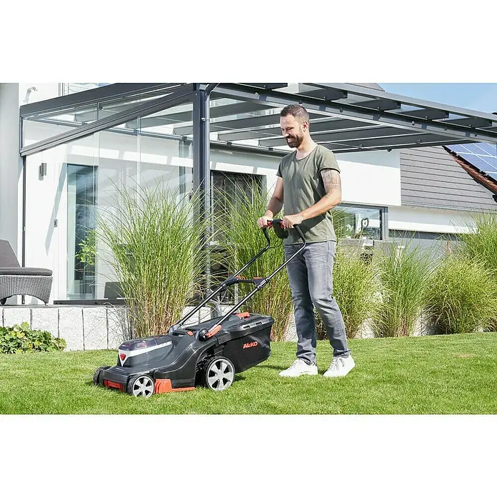 AL-KO Premium Akku-Rasenmäher 385 Li - 36 V, 1 Akku, 5 Ah, Schnittbreite: 38 cm - Ein Mann mäht den Rasen mit einem AL-KO Rasenmäher. Der Rasenmäher ist schwarz und hat orangefarbene Akzente.