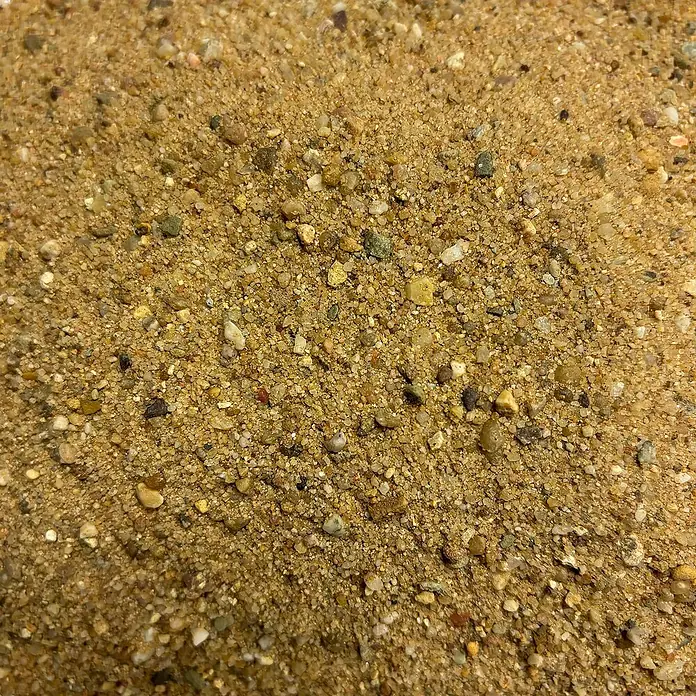Hamann Mercatus Estrichsand - Natur, Körnung: 0 mm - 4 mm, 25 kg - Nahaufnahme von grobem, gelblichem Sand mit kleinen Steinen, ideal für Bauprojekte und Gartengestaltung.