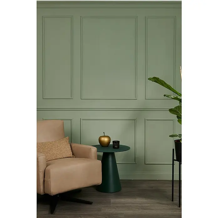 SCHÖNER WOHNEN-Kollektion Zierprofil Deckenleiste Elegant 1 - 2 m x 70 mm x 70 mm, Hochverdichtetes extrudiertes Polymer (HDPS) - Elegantes Interieur mit beigem Sessel, grünem Beistelltisch und goldenem Apfel, vor einer stilvollen, grün getäfelten Wand.