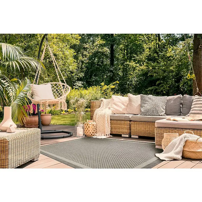 Outdoor-Teppich Newberry - Grau, 230 x 160 cm, 100 % Polypropylen - Einladende Outdoor-Szene mit einem grauen, strukturierten Teppich, der Komfort und Stil auf eine hölzerne Terrasse bringt.