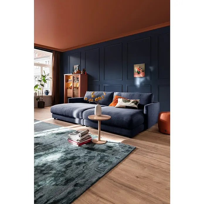 SCHÖNER WOHNEN-Kollektion Zierprofil Deckenleiste Elegant 1 - 2 m x 70 mm x 70 mm, Hochverdichtetes extrudiertes Polymer (HDPS) - Edles Wohnzimmer mit marineblauem Sofa, Terrakotta-Akzenten und stilvollem Teppich für ein gemütliches Ambiente.