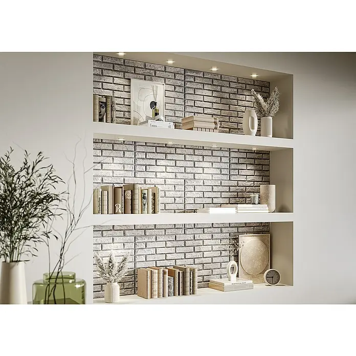 Nmc Decoflair Wandpaneel - Stone Wall Beton, 100 x 50 cm, Kunststoff - Regal mit grauer Ziegelrückwand, dekoriert mit Büchern, Vasen und Kunstwerken, die eine elegante Präsentation des Produkts zeigen.