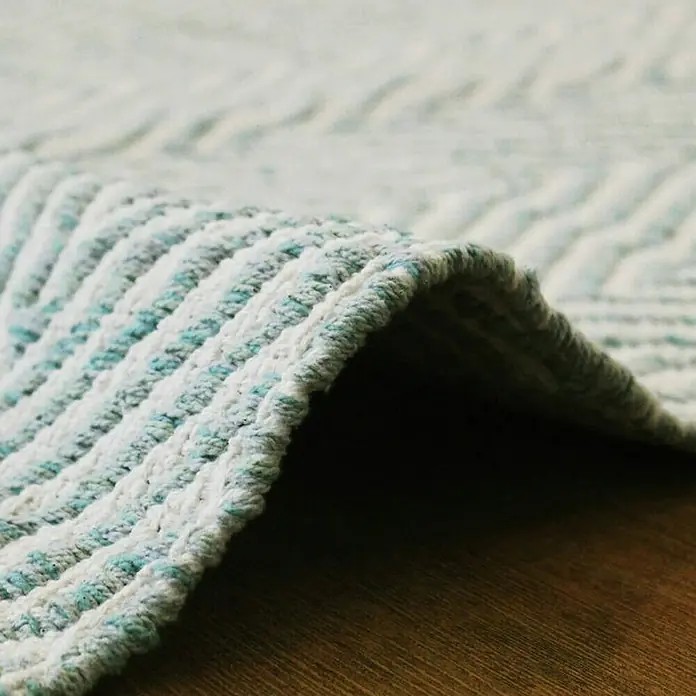 Kayoom Flachgewebeteppich Cocktail 400Türkis, 150 x 80 cm, 100% Baumwolle - Nahaufnahme eines hellen Teppichs mit türkisfarbenen Akzenten und einem gewebten Muster.