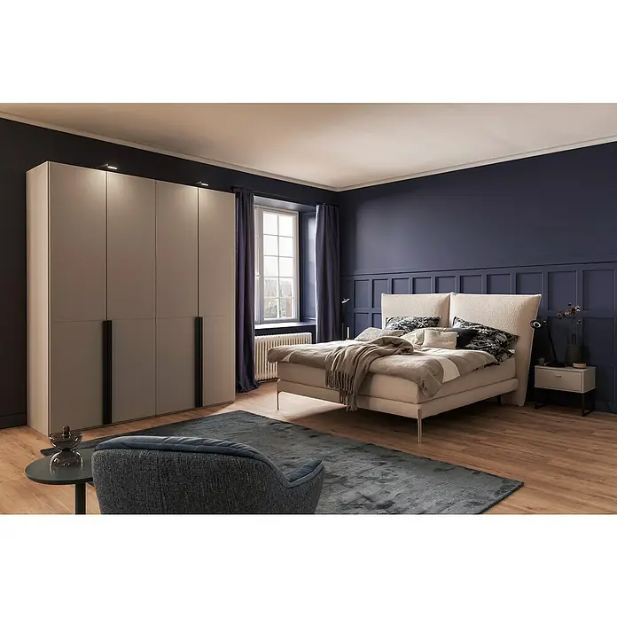 SCHÖNER WOHNEN-Kollektion Zierprofil Wandleiste Modern 3 - 2 m x 50 mm x 8 mm, Hochverdichtetes extrudiertes Polymer (HDPS) - Schlafzimmer mit großem Kleiderschrank, stilvollem Bett und gemütlichem Sessel auf einem dunklen Teppich. Elegantes Design für modernes Wohnen.