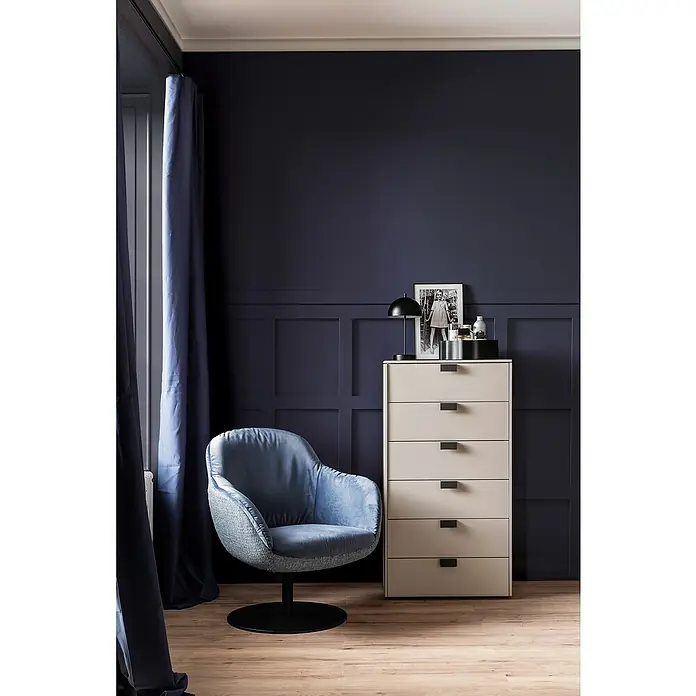 SCHÖNER WOHNEN-Kollektion Zierprofil Deckenleiste Modern 1 - 2 m x 45 mm x 45 mm, Hochverdichtetes extrudiertes Polymer (HDPS) - Elegantes Interieur mit blauem Sessel und beiger Kommode. Die Möbelstücke harmonieren perfekt mit der dunklen Wandfarbe im Hintergrund.