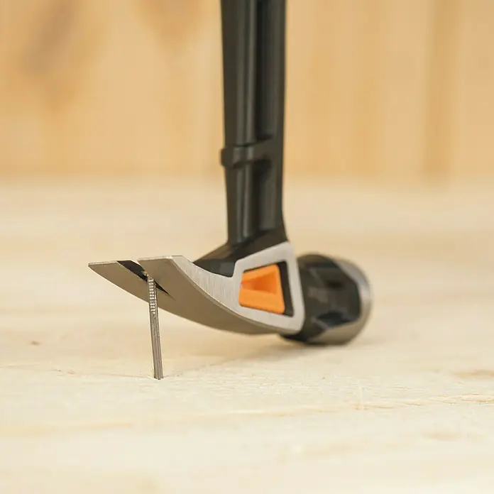 Fiskars Universalhammer M - Gewicht Kopf: 450 g, Länge: 340 mm - Nahaufnahme eines Hammers, der einen Nagel in ein Holzstück schlägt, wobei der Fokus auf der Funktionalität und Präzision des Werkzeugs liegt.