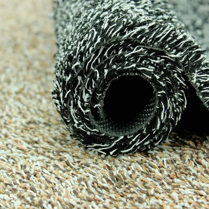 Felpudo Magic Mat - Multicolor, 75 x 45 cm - Primer plano de un felpudo enrollado en blanco y negro con propiedades atrapa-suciedad sobre una alfombra beige.
