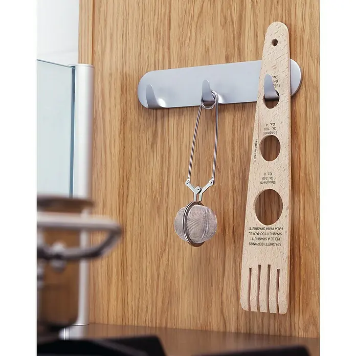 Tesa Powerstrips Colgador Multigancho - Plateado - Naturaleza muerta de cocina con un servidor de espagueti de madera y un infusor de té colgando de un gancho.