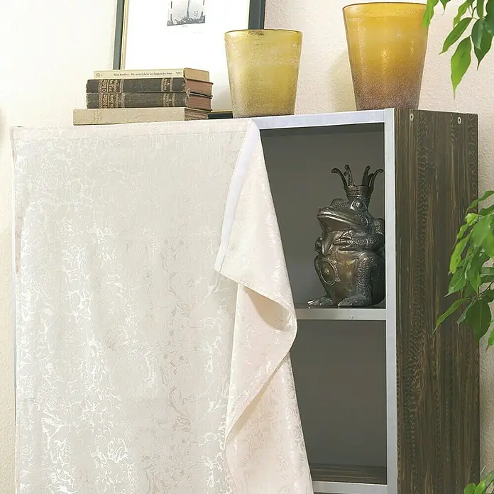 Tesa Cinta de velcro On & Off - 20 mm x 2,5 m, Negro - Una elegante cómoda con una cortina beige, decorada con libros, jarrones y una estatua de rana, ofrece un almacenamiento elegante.