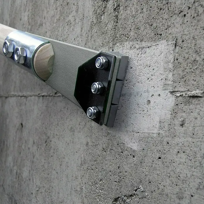 Berg Bauschaber - Länge: 1.180 mm, Blattbreite: 102 mm - Detailansicht einer an einer Betonwand befestigten Handlaufstütze aus Metall und Holz.