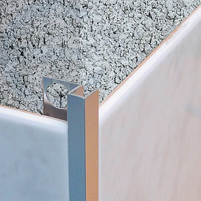 Perfil cuadrado multiusos - Aluminio, Negro, Mate - Primer plano de un borde de perfil de metal para azulejos, fijado a una pared alicatada, que proporciona un borde limpio y acabado.