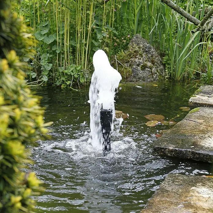 Ubbink Wasserspielpumpe Elimax 6000 - 125 W, Max. Förderhöhe: 390 cm - Teichbrunnen mit sprudelndem Wasser in einem üppigen Garten, der eine ruhige und entspannende Atmosphäre schafft.