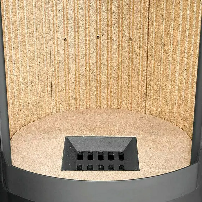 Justus Kaminofen Faro W+ 2.0 - 7 kW, Raumheizvermögen: 144 m³, Verkleidung: Stahl, Schwarz - Innenansicht eines Holzofens mit Steinauskleidung und Gussrost.