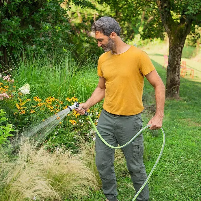 Fitt Gartenschlauch - Länge: 20 m, Schlauchdurchmesser: 13 mm - Ein Mann gießt mit einem Gartenschlauch Blumen. Der Wasserschlauch ist ein zentrales Element und wird von einem Mann im Garten benutzt.