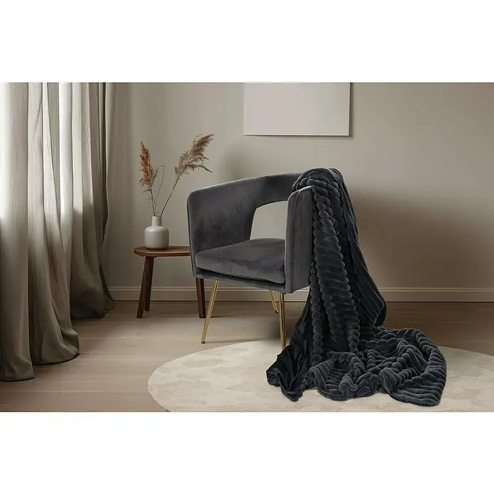 Decke Plush - Graphite, 200 x 150 cm, 100 % Polyester - Elegante Inneneinrichtung mit grauem Sessel und weicher, strukturierter Tagesdecke, die Stil und Komfort vereint.