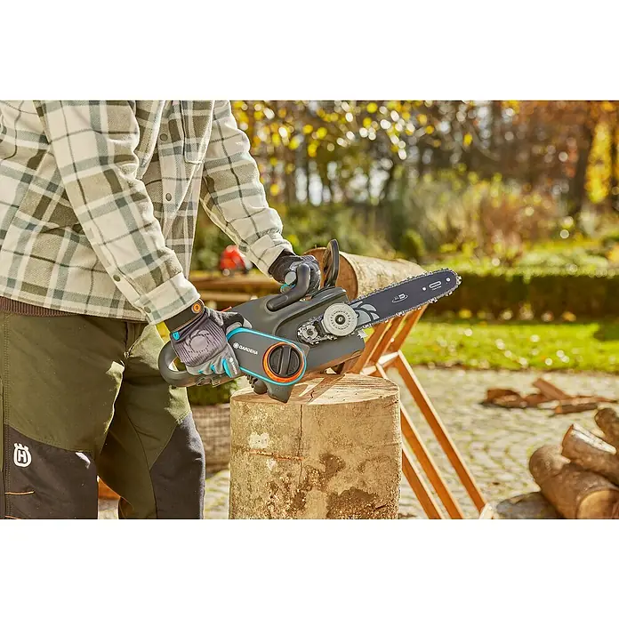 Gardena Power for All 18V Sägekette 3/8" - Passend für: Gardena Akku-Kettensäge PowerSaw 250/18V - Eine Person bedient eine GARDENA Akku-Kettensäge auf einem Holzscheit, umgeben von herbstlicher Natur.