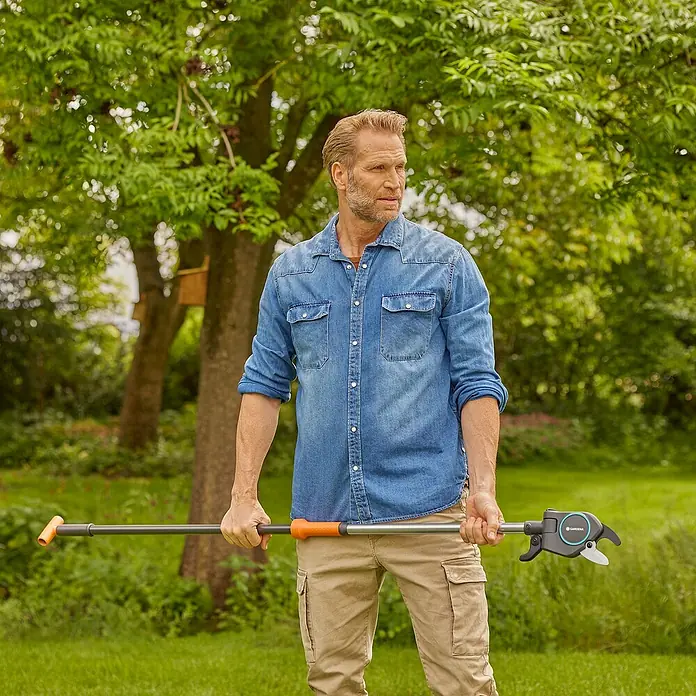 Gardena StarCut Baumschere Pro S - Max. Aststärke: 32 mm - Ein Mann im Garten hält eine Gardena Astschere mit Stiel in den Händen, bereit für die Gartenarbeit. Ideal für schwer erreichbare Äste.