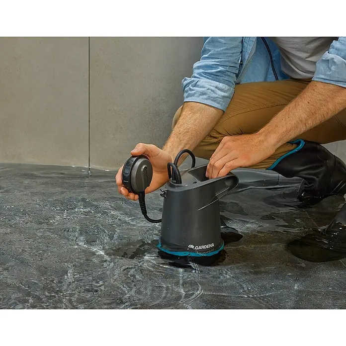 Gardena Klarwasser-Tauchpumpe 20000 Basic - 550 W, Max. Fördermenge: 20.000 l/h - Eine GARDENA Schmutzwasser-Tauchpumpe wird in einem überfluteten Bereich von einer Person mit Stiefeln bedient.
