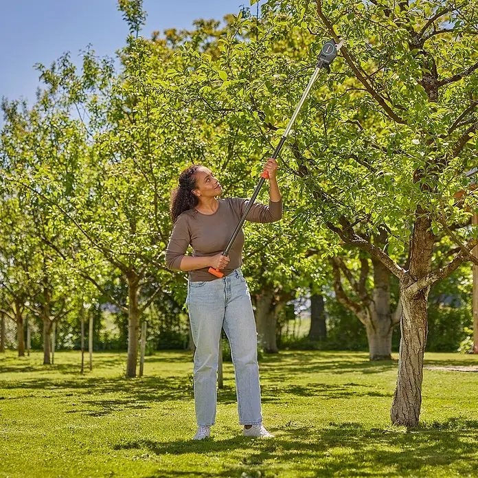 Gardena StarCut Baumschere Pro S - Max. Aststärke: 32 mm - Eine Frau benutzt eine GARDENA Hochentaster zum Beschneiden eines Baumes in einem Garten, wobei der Fokus auf dem Werkzeug liegt.