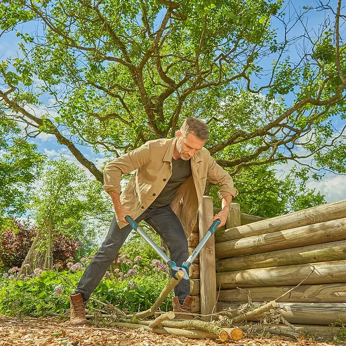 Gardena EasyCut Astschere L - Länge: 670 mm - Mann schneidet Äste mit einer Gartenschere unter einem Baum, umgeben von üppigem Grün.