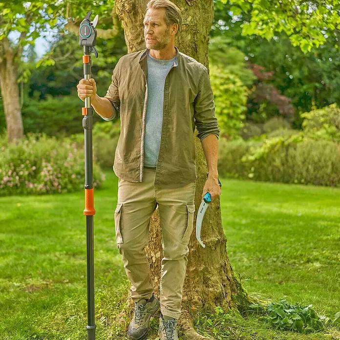 Gardena StarCut Astsäge - Länge: 59,4 cm, Passend für: GARDENA Baum- und Strauchschneider StarCut Pro L - Mann mit einer Gardena Astschere und einer Säge im Garten. Die Astschere ist teleskopierbar und ermöglicht das Schneiden von Ästen in großer Höhe.