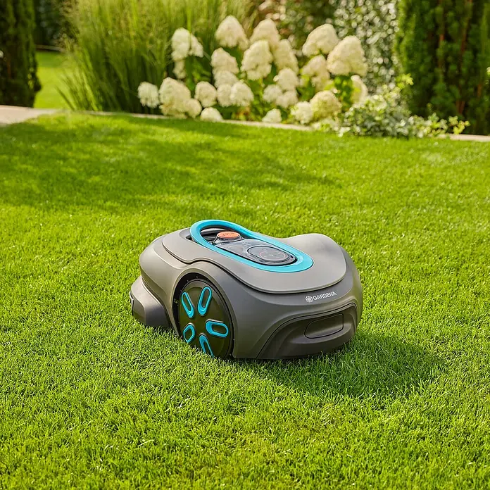 Gardena Mähroboter smart SILENO max - 1.500 m², Schnittbreite: 22 cm, Induktionsgestützte Navigation, Begrenzungskabel - Ein grauer Gardena Mähroboter mit blauen Akzenten steht auf einem saftig grünen Rasen. Das Gerät ist bereit zum Einsatz.