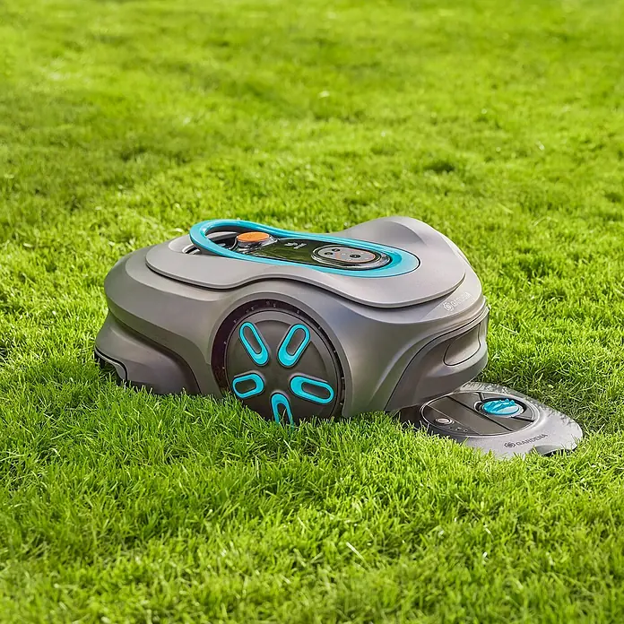 Gardena Sprinklersystem Versenkregner-Set AquaPrecise Basis - Max. Regnerfläche: 320 m², Reichweite ca.: 2 m - 10 m - Der Gardena Mähroboter auf dem grünen Rasen. Er ist grau mit blauen Akzenten und bereit für den Einsatz im Garten.
