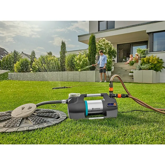 Gardena Sauggarnitur 25 mm 1" 7 m - Durchmesser: 25 mm, Länge: 7 m - Gardena 6200 SilentComfort Gartenpumpe im Einsatz, bewässert einen grünen Rasen mit einem Sprinkler, während eine Person mit Schlauch gießt.