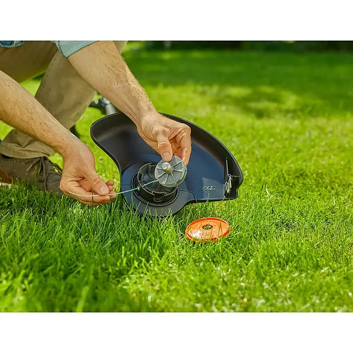 Ersatzfadenspule - Fadenlänge: 4 m, Fadenstärke: 2 mm, Passend für: PowerTrim-Modelle von GARDENA - Ein Mann wechselt die Spule an einem Rasentrimmer auf einer Rasenfläche. Der Trimmerkopf und die Spule sind im Fokus.