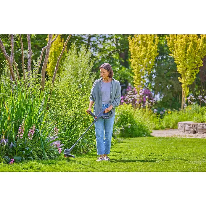 Gardena Power for All 18V Akku-Rasentrimmer EasyTrim 25/18V - 18 V, 2 Ah, Li-Ionen, 1 Akku, Schnittbreite Faden: 25 cm - Eine Frau, die mit einem Akku-Rasentrimmer in einem üppigen Garten arbeitet, wobei der Fokus auf dem Gartengerät liegt.