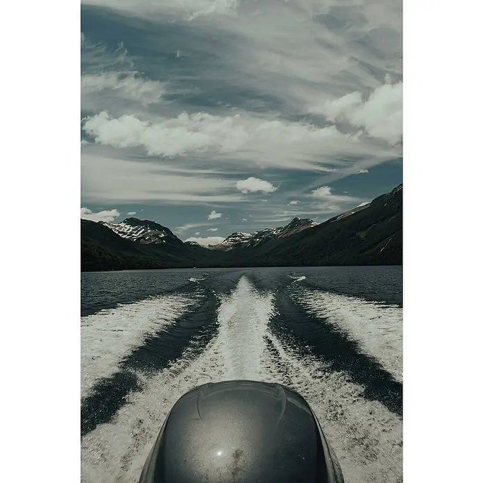 Elektropumpe - 12 V, Max. Fördermenge: 680 l/min - Bootsfahrt auf einem See mit Blick auf bewaldete Berge und einen bewölkten Himmel.