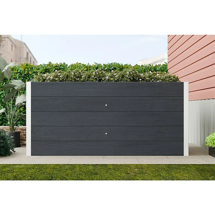 Hochbeet WPC - 160 x 75 x 70 cm, Verbundwerkstoff, Anthrazit - Eine graue Pflanzkiste mit weißen Akzenten und grünen Pflanzen, die oben herausragen, auf einer gepflasterten Terrasse.
