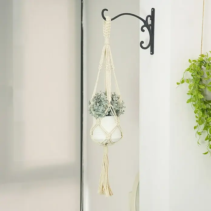 Blumenampel Makramee - Ø x H: 4 x 85 cm, Beige - Ein dekorativer Makramee-Pflanzenhänger mit Topf und Pflanze, der an einer verzierten, schwarzen Wandhalterung befestigt ist.