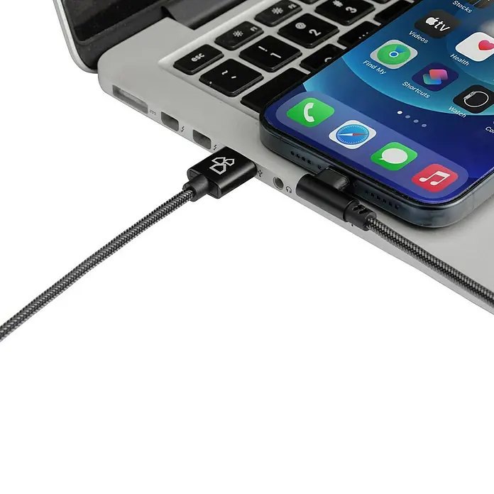 BAUHAUS USB-Ladekabel Winkel - Schwarz, 1 m, USB A-Stecker, USB C-Stecker - Nahaufnahme eines iPhones, das mit einem geflochtenen USB-Kabel an einen Laptop angeschlossen ist und den Ladevorgang zeigt.