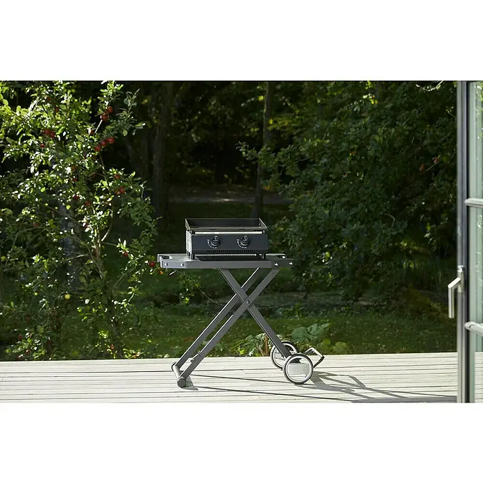 Cozze Plancha-Grill G 400Grillfläche (B x T): 48 x 35 cm, Anzahl Brenner: 2 Stk., Schwarz - Tragbarer, schwarzer Gasgrill auf einem grauen Rollwagen im Freien auf einer Holzterrasse, ideal für kulinarische Erlebnisse im Garten.