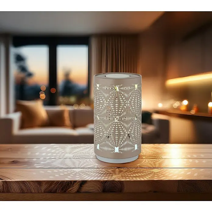Globo Akku-Tischleuchte Amiyazh - Champagn, Durchmesser: 8 cm, RGBW - Nahaufnahme einer dekorativen Lampe mit kompliziertem Muster, die ein warmes Licht auf einen Holztisch wirft und eine gemütliche Atmosphäre schafft.