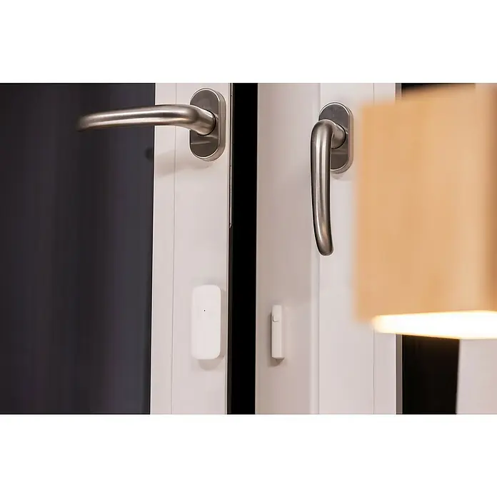 Osram Fenster- & Türsensor-Set Kontaktsensor - Weiß - Nahaufnahme eines weißen Fensters mit Griffen und einem angebrachten weißen Fensterkontakt für die Sicherheit.