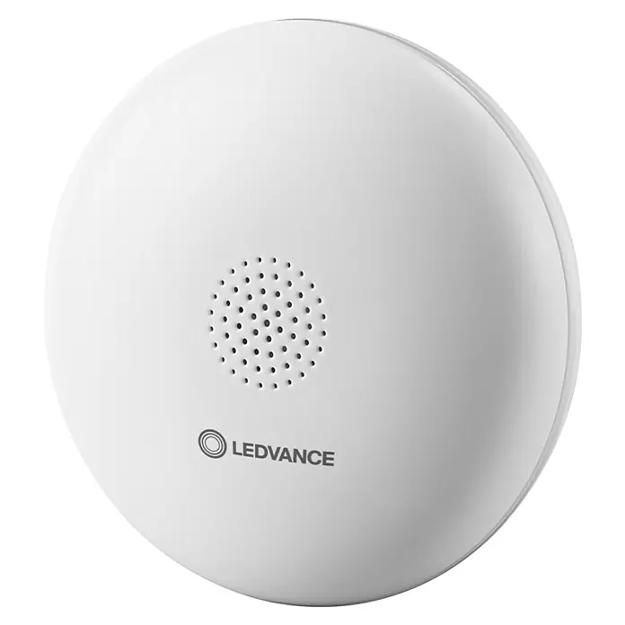 Ledvance Smart+ WiFi Wassermelder - Anwendungsbereich: Innen, Passend für: Google Home - Das Bild zeigt ein LEDVANCE Smart+ WiFi Bewegungsmelder, ein weißes, rundes Gerät mit Lautsprecher und Logo auf schwarzem Hintergrund.