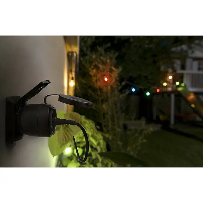 Osram Smart-Steckdose mit Deckel matter - Außen, IP44, Schwarz, 16 A, 1 Stk. - Das Bild zeigt eine wetterfeste Steckdose im Außenbereich, an die ein Stromkabel angeschlossen ist, ideal für Gartenbeleuchtung und andere Geräte.